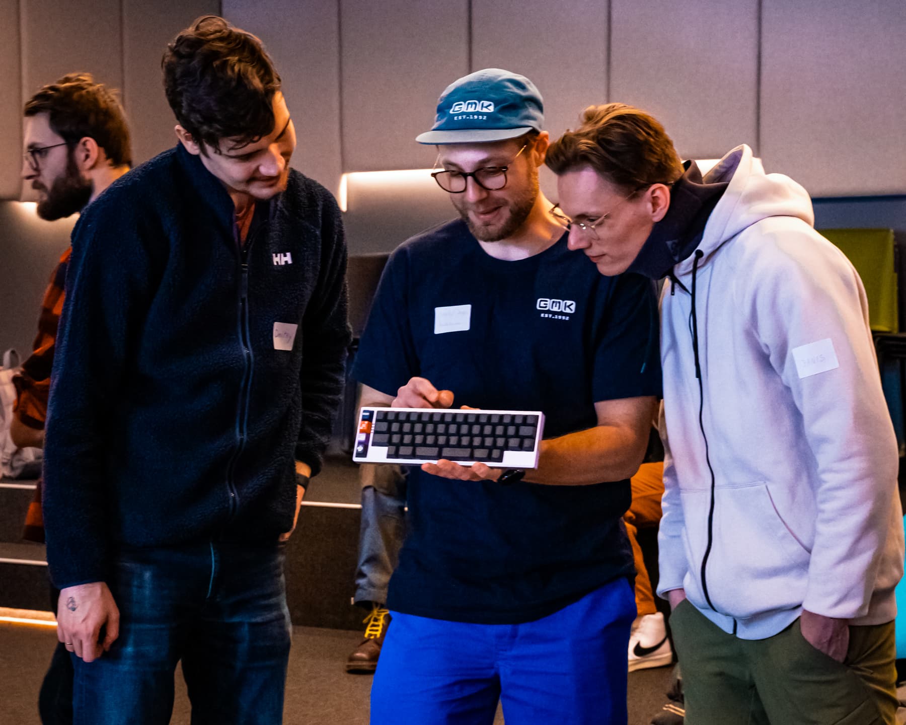 Three people looking at a keyboard.